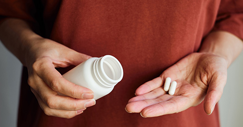 A woman pouring pills into her hand.