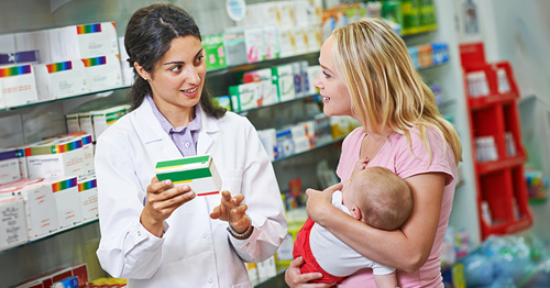 A pharmacist speaking with a mother holding her infant.