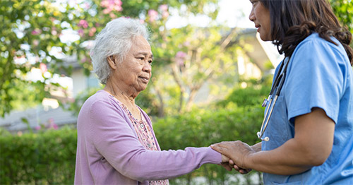 An older woman with a female doctor in a garden setting.