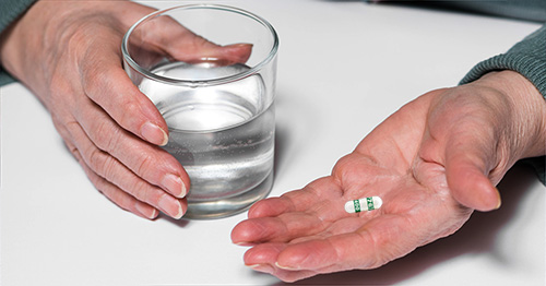 A hand holding a celecoxib capsule.