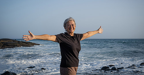 Smiling senior woman holding her arms outstretched.