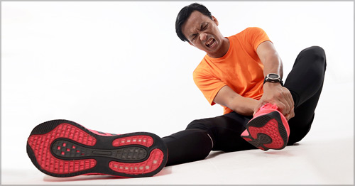 A man grabbing his Achilles tendon area in pain.