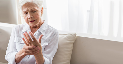 A woman grasping her hand in pain.