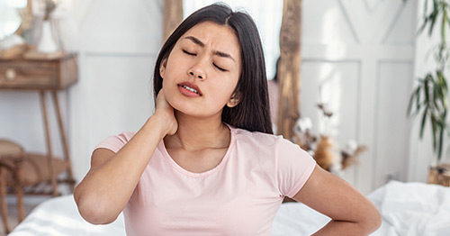 A woman holding her neck in pain.