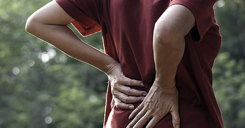A woman holding her back in pain.