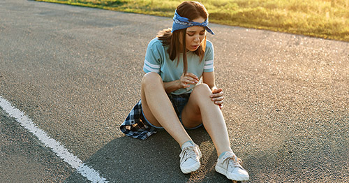 A girl grabbing her knee in pain.