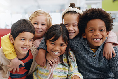 photo of children laughing and smiling with arms around each other