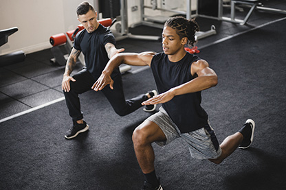 photo of a male exercise physiologist working with a young male athlete in a gym setting