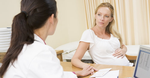 A pregnant woman speaking with a doctor.