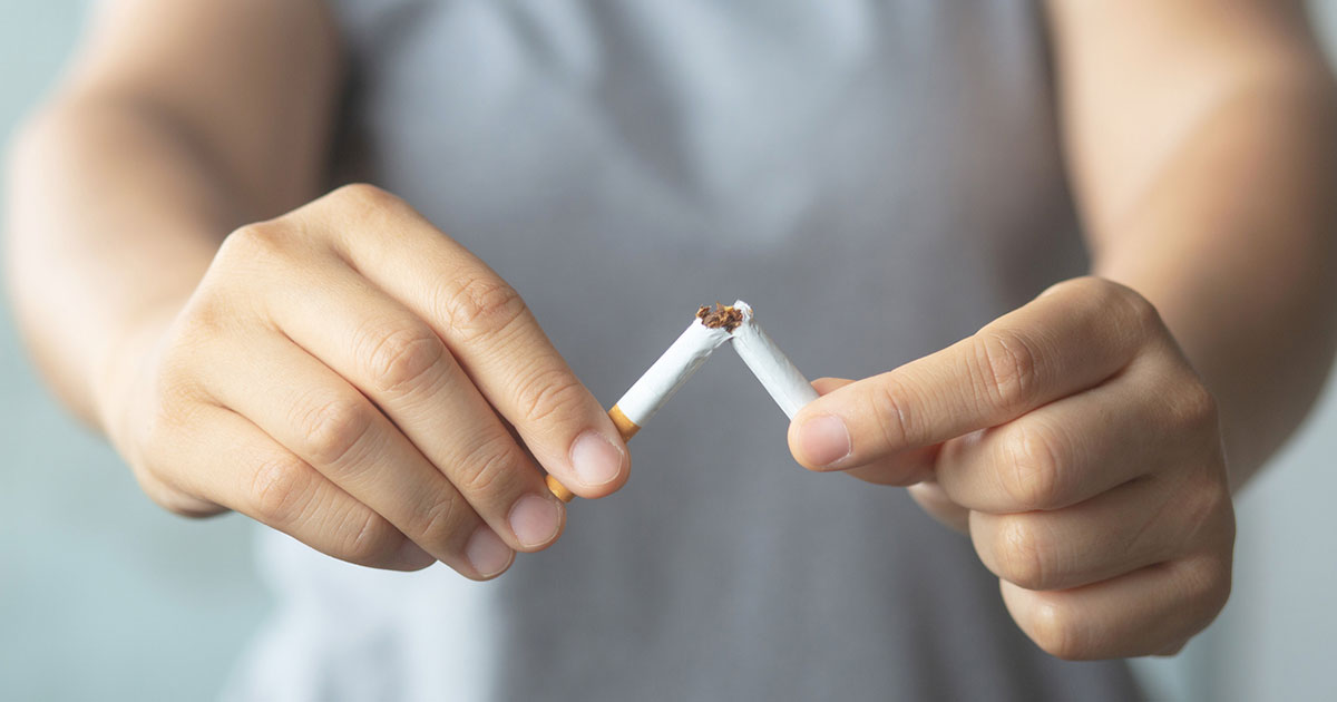 A person breaking a cigarrete in half.